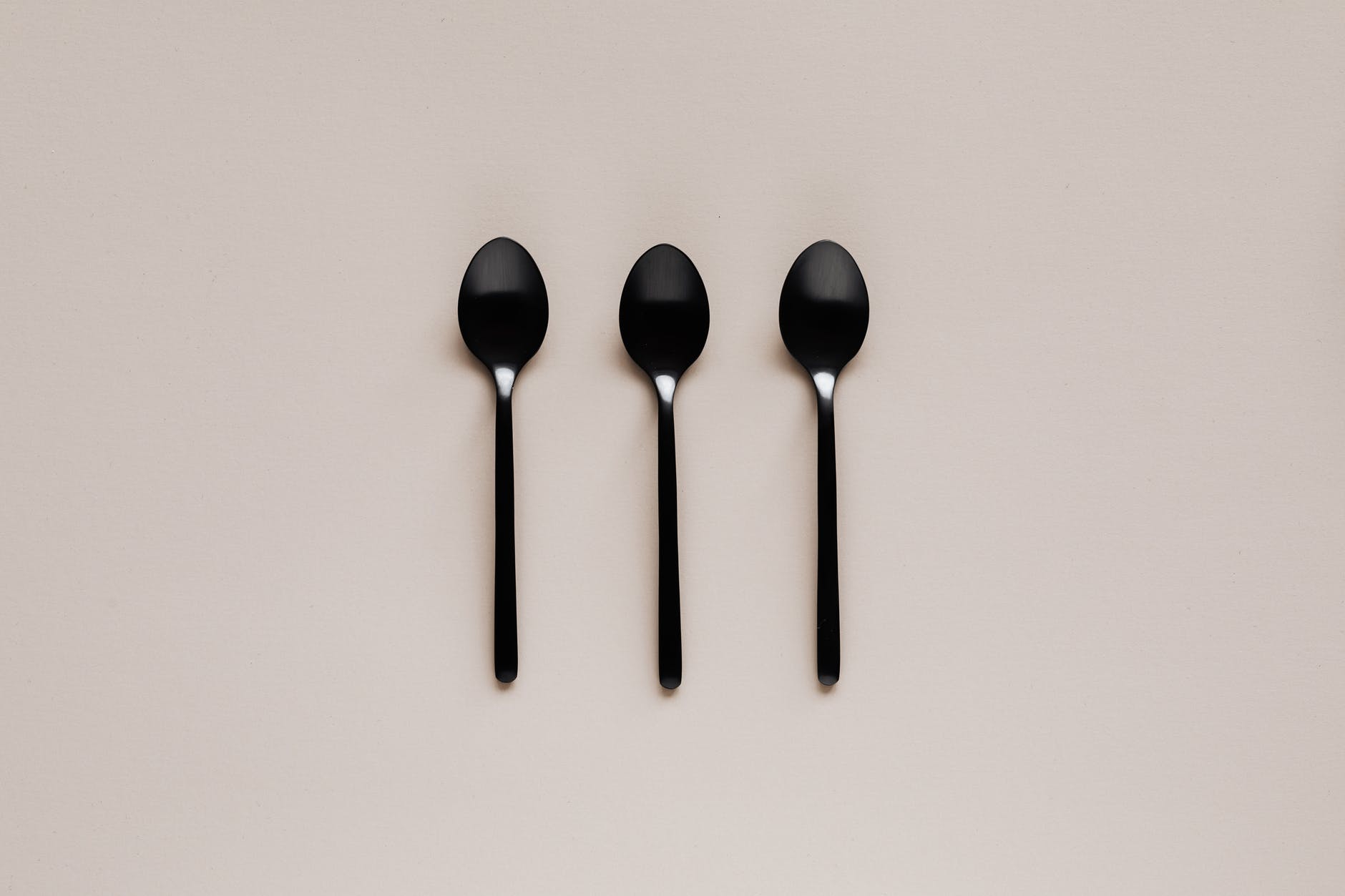 set of black teaspoons on beige surface